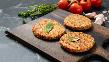 Vegetables patties or cutlets for vegan burgers on wooden cutting table, black marble background.