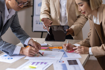 Group of confident business people point to graphs and charts to analyze market data, balance sheet, account, net profit to plan new sales strategies to increase production capacity.	