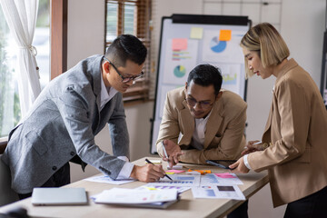 Group of confident business people point to graphs and charts to analyze market data, balance sheet, account, net profit to plan new sales strategies to increase production capacity.	