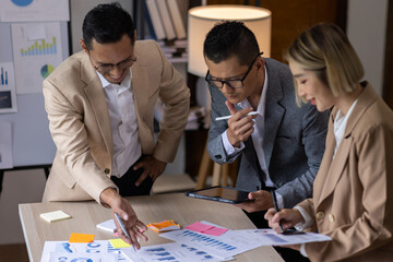 Group of confident business people point to graphs and charts to analyze market data, balance sheet, account, net profit to plan new sales strategies to increase production capacity.	