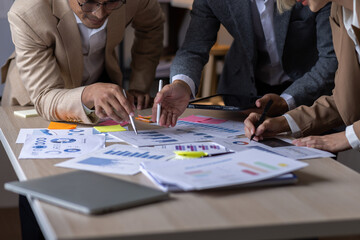 Group of confident business people point to graphs and charts to analyze market data, balance sheet, account, net profit to plan new sales strategies to increase production capacity.	