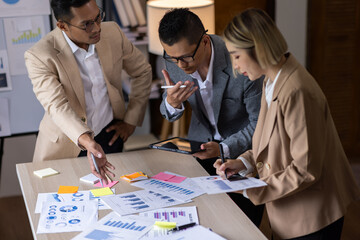 Group of confident business people point to graphs and charts to analyze market data, balance sheet, account, net profit to plan new sales strategies to increase production capacity.	