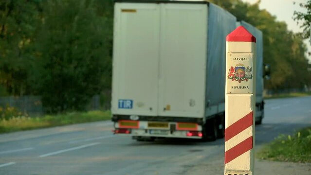 static close up shot of border sign of the Republic of Latvia, bus drives by in background