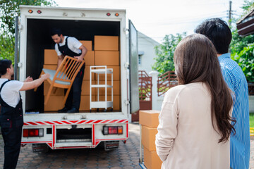 Asian Couple check while unloading boxes and furniture from a pickup truck to a new house with...