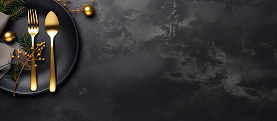 A banner with golden cutlery on a black stone table, representing a table setting for Christmas or New Year. It can be used as a card, menu template, or for any other purpose. has copy space and