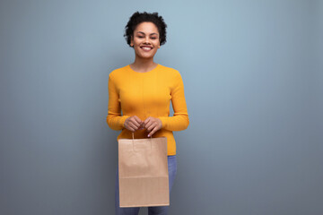 smiling young hispanic woman with black curly hair holding craft bag