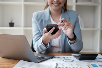 Fototapeta premium Close up view of female office worker working with laptop and using smartphone in the same time.