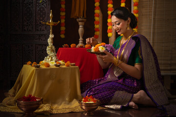 Portrait of Indian young lady performing Hindu rituals of pooja and celebrating the Hindu festival Diwali. Celebration of the Indian festival by young Indian Lady. Diwali festival celebration. - obrazy, fototapety, plakaty