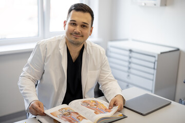 Portrait of urologist sitting with a book in a medical office. Concept of portraits of real doctors