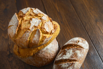 Stack of different loaves of bread on a wooden table with copy space