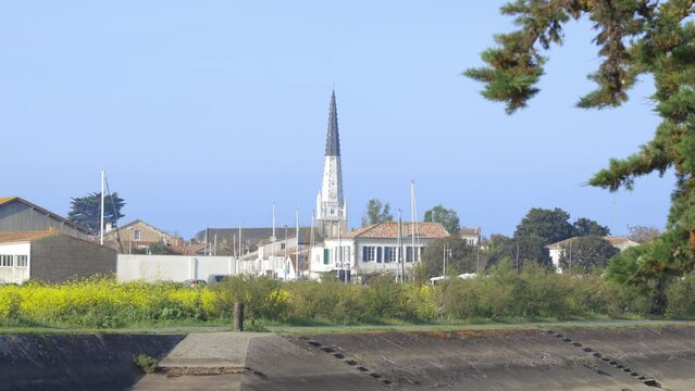 Black and white bell tower of Sainte-Etienne church in Ars-en-R&eacute;, France seen from the canal