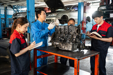 A middle-aged Asian senior male mechanic in blue uniform, standing to explain about the car engine...
