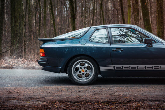 Dark blue Porsche 944 in autumn forest. Rear quarter side profile view of 1980s sportscar. Kyiv, Ukraine - November 26 2017.