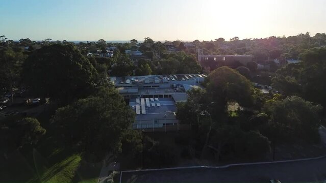 4k drone video flying above football field over the building and turning right to reveal sea at Mentone