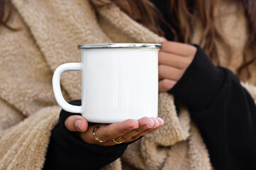 Girl is holding enamel camping mug in hands. Blank enamel white cup. Blank mug printing design...
