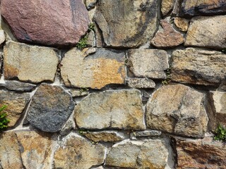Steinwand aus großen Steinen in Braun, Rot, Orange als Nahaufnahme