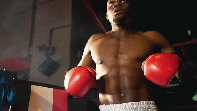 The boxers are resting and taking deep breaths in the corner of the boxing ring before gathering their strength and fighting again.
