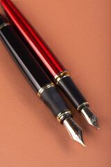 Fountain pens, beautiful fountain pens placed on brown leather surface, selective focus.