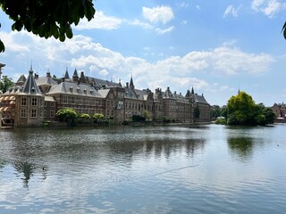 Landscape of Dutch government headquarters building The 
Binnenhof in The Hague Netherlands Holland city centre looking across large water area with beautiful trees and balustrade walk way Summer day 