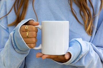 Girl is holding white mug in hands. Blank 11 oz ceramic cup. mug mockup with copy space