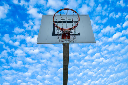 High basketball hoop with blue sky and clouds scenery