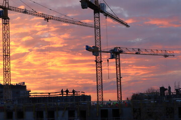 builders and construction crane at sunset