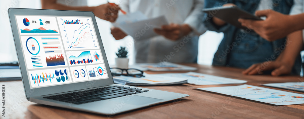 Poster Focus BI power dashboard display on laptop screen with blurred background of analyst team analyzing business financial data using BI Fintech software for business insight. Panorama shot. Scrutinize