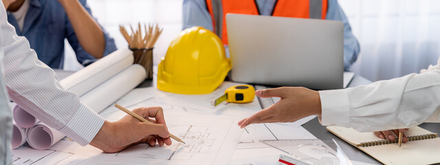 Engineer partner drawing and working on blueprint design together on office table for architectural...