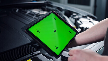 Unrecognizable male car service worker checking car and doing maintenance using a digital tablet computer with green screen chromakey, while standing near the opened bonnet © wedmoments.stock