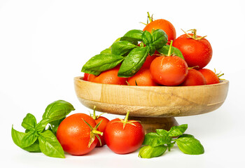 Red tomatoes and fresh basil in a wooden plate, on a white background. Home gardening. Eating healthy.
