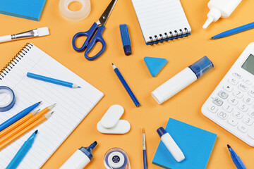 Assorted office and school white and blue stationery on bright yellow background. Organized knolling for back to school or education and craft concept. Selective focus. filled frame