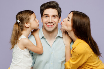 Close up young smiling happy parents mom dad with child kid daughter girl 6 years old wear blue yellow casual clothes try to kiss father husband isolated on plain purple background Family day concept