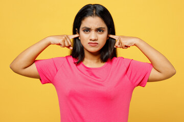 Young indignant sad Indian woman wearing pink t-shirt casual clothes cover ears with hands fingers...