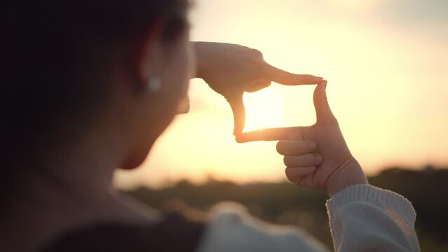 B roll - travel freedom a concept, Close up of traveler woman hands making frame gesture with sunset in summer, Female capturing the sunrise