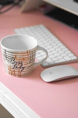 White ceramic mug resting on a desktop computer desk next to a computer mouse