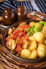 Fried pieces of chicken with red peppers and onions.