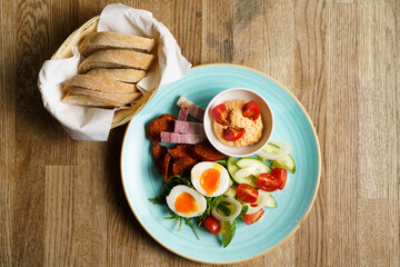 Soft Boiled eggs with vegetables, ham and sausage on a plate