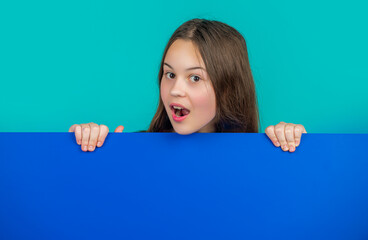 surprised kid behind blank blue paper with copy space for advertisement