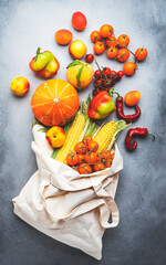 Autumn vegetables and fruits from local farm market in beige linen reusable eco-friendly bag, healthy vegan shopping, gray background, top view