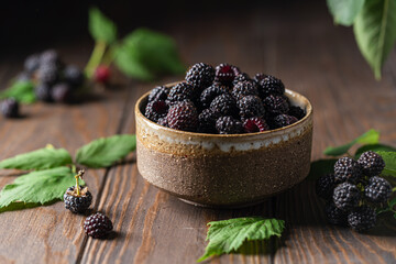 Organic fresh black raspberry in a bowl on dark wooden background