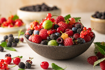Various fresh berries in a bowl. Mix of different fresh berries on white background. Strawberries, raspberries, gooseberries and cherries are presented.