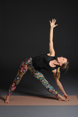 Woman doing yoga in photo studio on isolated grey background.	
