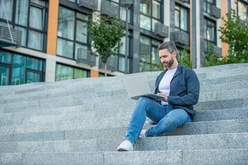 freelancer man with laptop sit outdoor. freelancer man in the street. freelancer man with pc outside