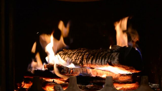 Closeup footage of burning wood in the fireplace against the black background