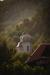 Obraz premium Vertical shot of an old church on a hill surrounded by trees.