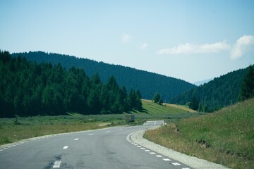 Fototapeta premium Beautiful view of an asphalt road through green hills under a blue sky.