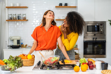 Diversity young happy love LGBT, LGBTQ caucasian and african family lesbian couple woman cook vegan food healthy eat with fresh vegetable salad in kitchen at home, pride, rainbow.Lgbt lesbian couple - obrazy, fototapety, plakaty