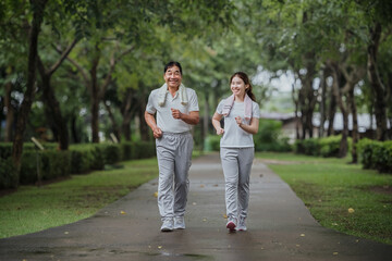 Young beautiful asian woman jogging with her father in park happily, with a smile. Asian woman jogging with her father for health care, park exercise, health care. concept health care life insurance.