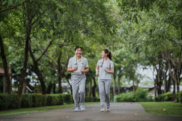 Fototapeta na wymiar Young beautiful asian woman jogging with her father in park happily, with a smile. Asian woman jogging with her father for health care, park exercise, health care. concept health care life insurance.