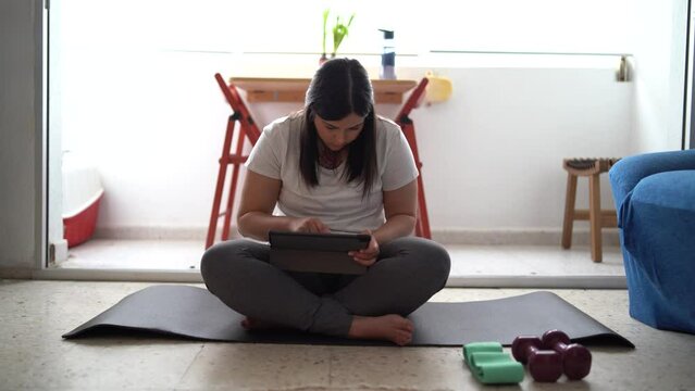 Caucasian woman finding an exercise online by her tablet to do at home